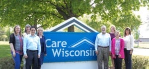 8 members of My Choice Wisconsin's executive team stand outside the Dane County office in front of My Choice Wisconsin's sign