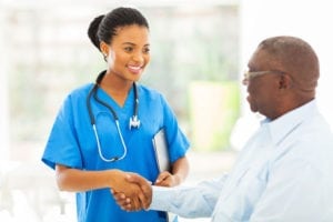 A nurse with a stethoscope smiles at a patient and shakes his hand