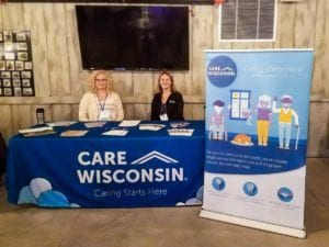 Two women sit behind a CW themed conference table